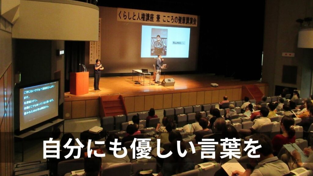 井原市人権講演会のステージで歌う石川達之