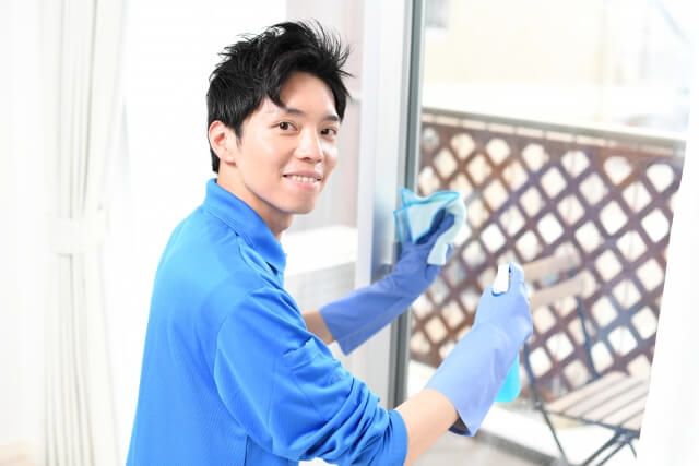 窓ガラスを掃除する若い男性