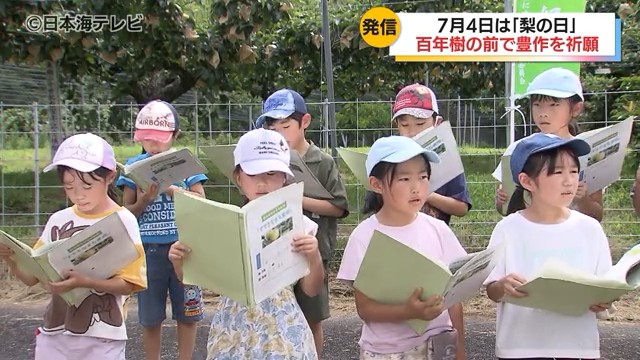 梨の日の話題のテレビニュースで小学生が「梨のうた」を合唱するシーン