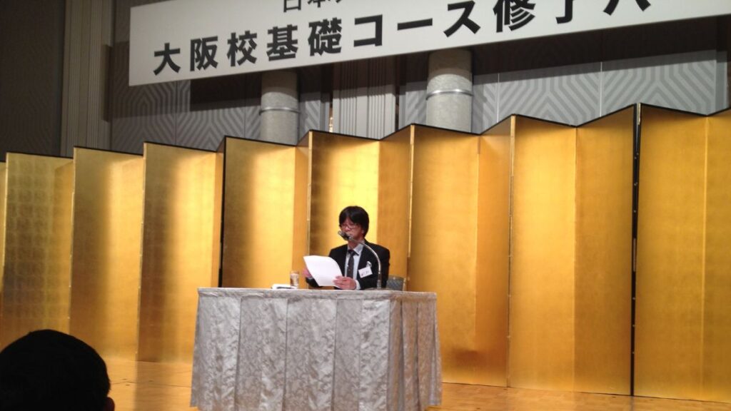 日本メンタルヘルス協会の修了式でレポートを朗読する石川達之